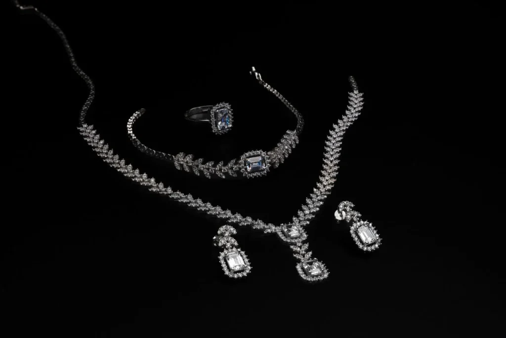 Lab grown diamond jewellery set featuring a necklace, earrings, bracelet and ring on a black background.