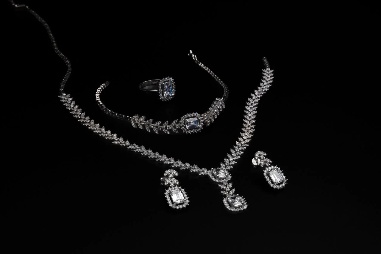 Lab grown diamond jewellery set featuring a necklace, earrings, bracelet and ring on a black background.
